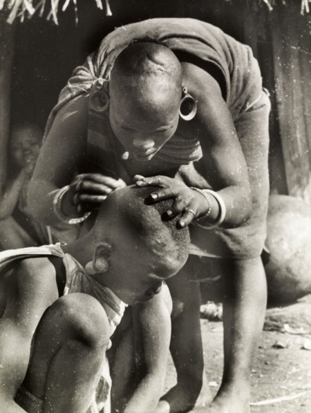 A Kikuyu mother de-louses her daughter. A Kikuyu mother bends over to de-louse her daughter's