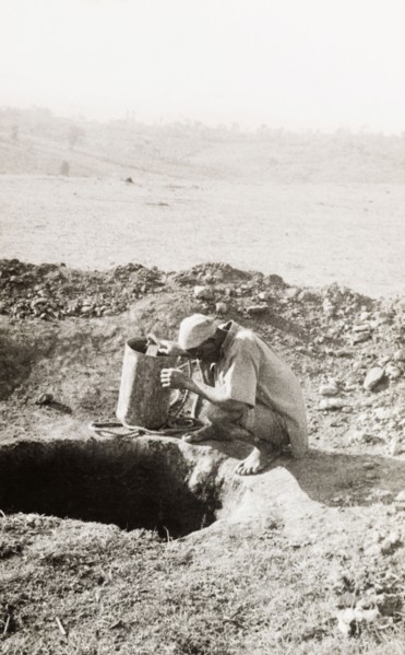 Exploratory mine shaft at the Kakamega goldfields. A labourer squats at the opening to a mine shaft