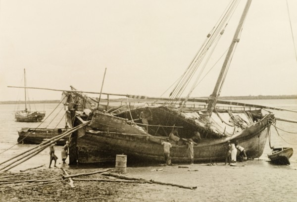 Repairing a dhow at Lamu, Kenya. Men repair a dhow, which is dry-docked on a beach at Lamu. Lamu,