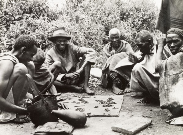 Telling fortunes by beans'. A group of Kikuyu men gather around to read their fortunes by