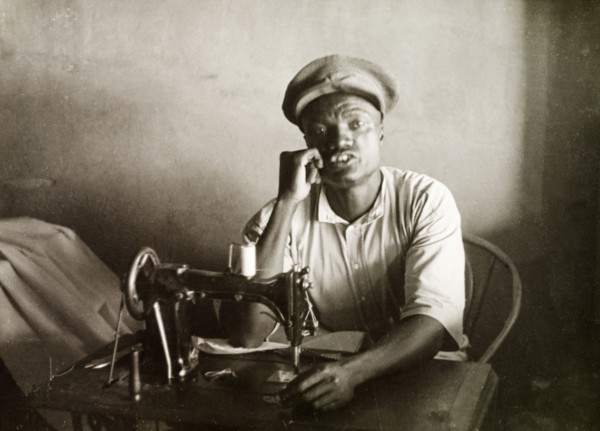 A Swahili tailor. A Swahili tailor sits behind a sewing machine at his work desk in Mombasa.