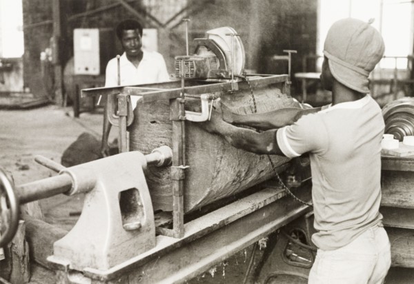 Craftsman operating a lathe, Ghana. A craftsman operates a wood-turning lathe to shape a section of