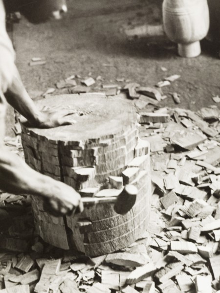 Shaping the shell of an atumpan drum. A craftsman uses a mallet on a section of timber, knocking