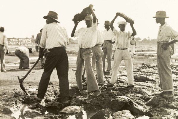 Labourers dig asphalt at the Pitch Lake. Labourers use pickaxes to extract lumps of asphalt from