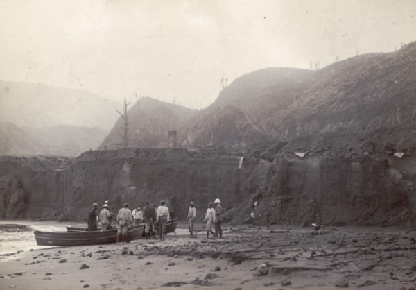 Wallibu dry river. Men stand beside canoes on the muddy bed of Wallibu River. The river was forced