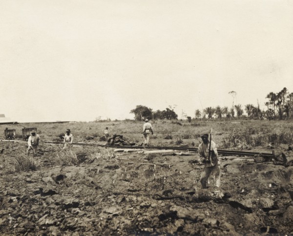 Labourers dig asphalt at the Pitch Lake. Labourers use pickaxes to extract lumps of asphalt from