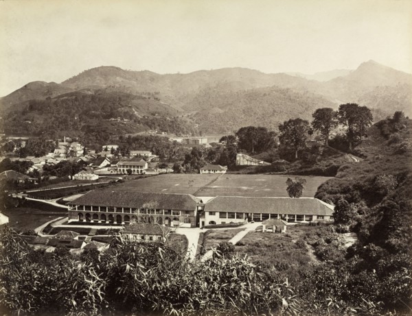 The Barracks', Kandy. A double-storey colonnaded building with a recreation ground. Identified by