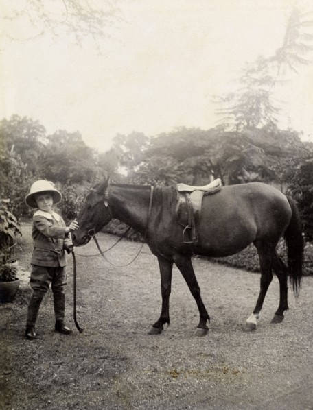 Owen with a pony, India. A European boy, Owen, wears a solatopi hat as he poses for the camera