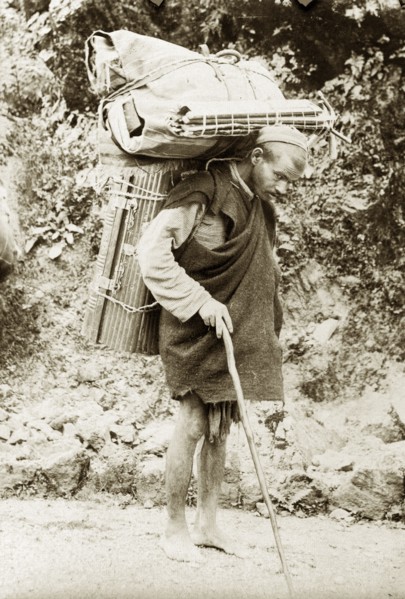 Burdened with luggage. An Indian man carries cumbersome bundles of luggage on his back as he walks
