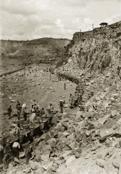 Rail carts at the Premier Diamond Mine. African labourers load rail carts full of rubble at the
