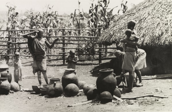 A Kikuyu family pottery'. Three Kikuyu women look after several small children as they make clay