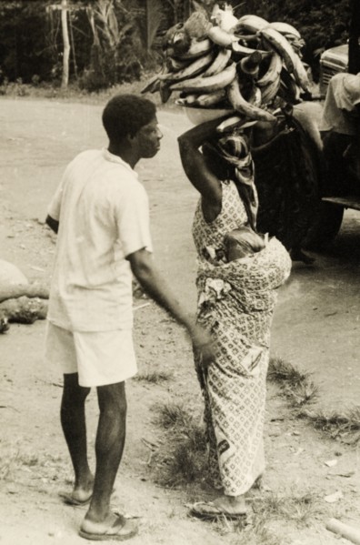 Gold Coast courtesy'. A man helps his wife to arrange her load as she attempts to balance a bowl of