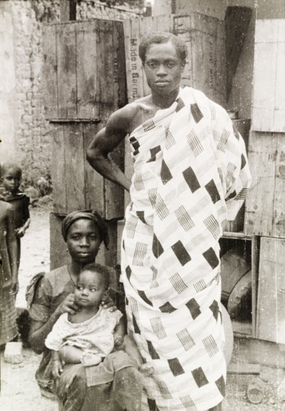 An Asante family. An Asante (Ashanti) man stands beside his seated wife and baby, wearing a