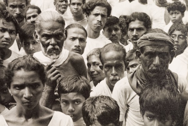 A crowd of Ceylonian people. A tightly packed crowd of people gaze solemnly into the camera. Ceylon