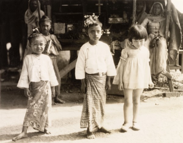 Children in Rangoon. A young British girl poses with two Burmese children wearing traditional