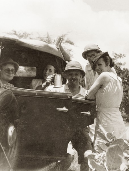 Friends socialising, Calcutta. A group of friends socialise by a motor car, one man raising up a