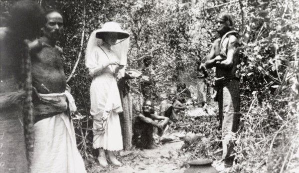 Ceylonian beaters on elephant drive. A European woman stands in a jungle clearing with a team of