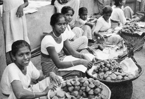 Short-eats' in Ceylon. A row of female traders sit on a city street, selling deep-fried