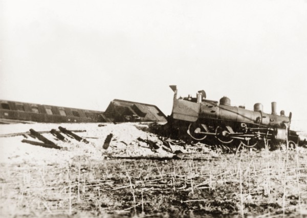 Derailed steam locomotive at Ras el Ain. A steam locomotive lies in pieces on a railway embankment,