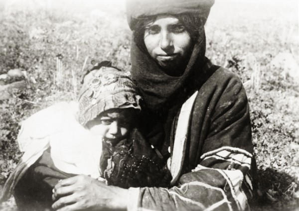 Bedouin mother and child, Palestine. A young bedouin mother cuddles her baby on her lap. British