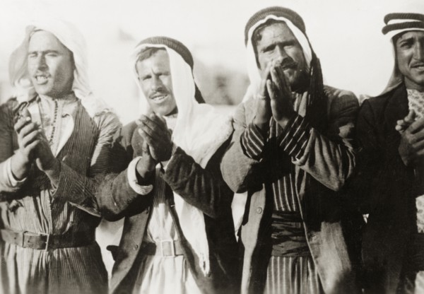 Pilgrims at a Nebi Musa procession. Four Arab men clap their hands together as they take part in a