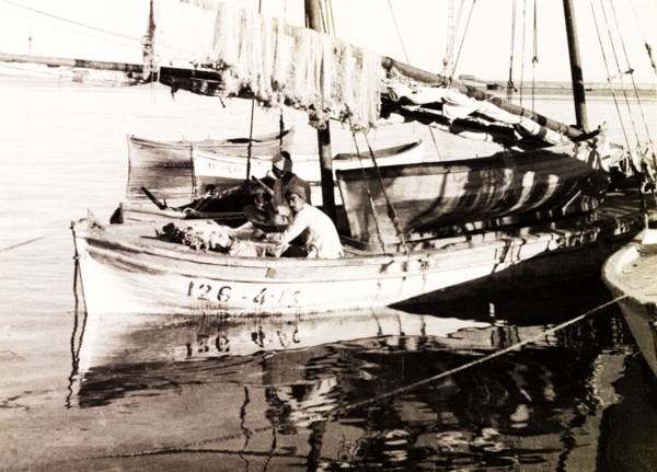 Fishing boat on the Suez Canal. Two fishermen sit aboard a stationary sail boat on the Suez Canal,