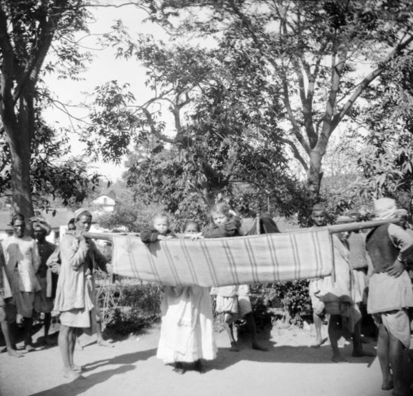 Children travelling in a sedan chair. An Indian ayah (nursemaid) watches over two European children