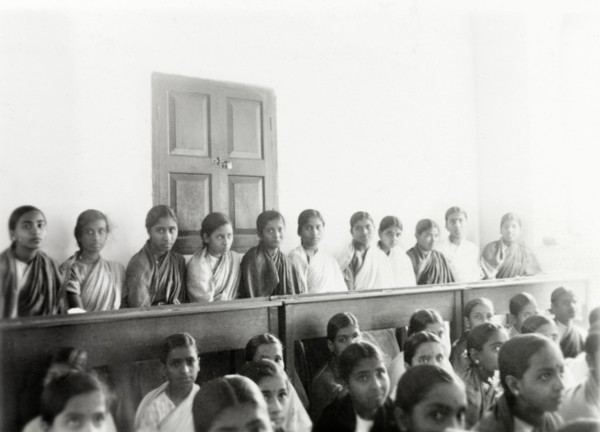 Students at girl's high school, Mysore. Rows of female Indian students sit on benches in a