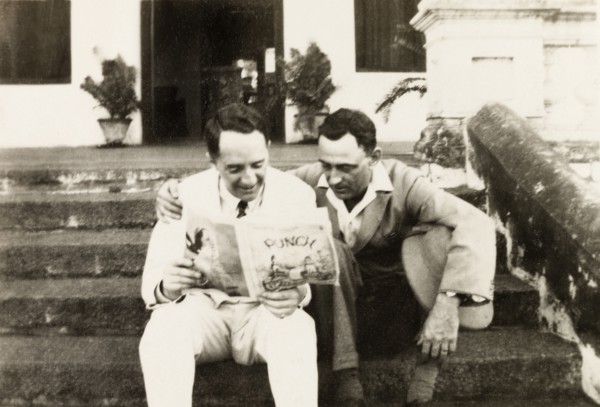 Reading 'Punch' magazine. Mr Moulton and Mr Horler sit on the steps of the United Theological