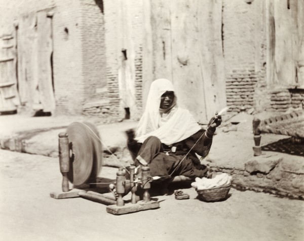 Silk spinner, India. An Indian woman sits by the roadside spinning silk using a 'charkha' or