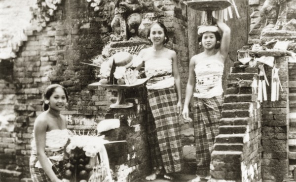 Balinese women posing on temple steps. Three young Balinese women wearing traditional 'kain sarung'