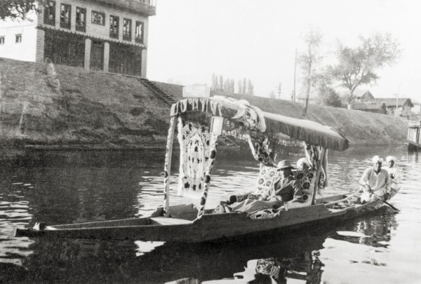 Water taxi on a Srinagar canal. Majid Ullah in the shikari 'Blue Heaven' as he is ferried along a