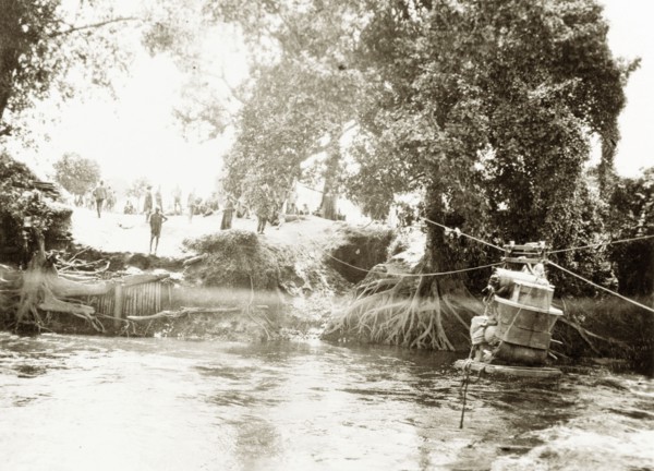 Transporting luggage across a river. A pile of luggage is stacked onto a raft, ready to be hauled
