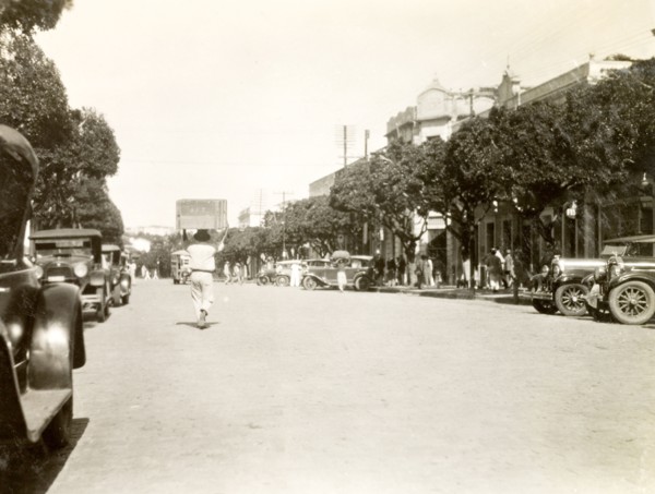 City street in Natal, Brazil. Pedestrians mill about on a wide, tree-lined street in the centre of