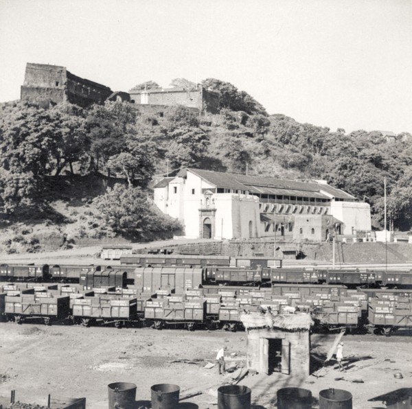 Rail sidings at Mormugao port. Empty freight cars sit on sidings beneath a prominent fortress at