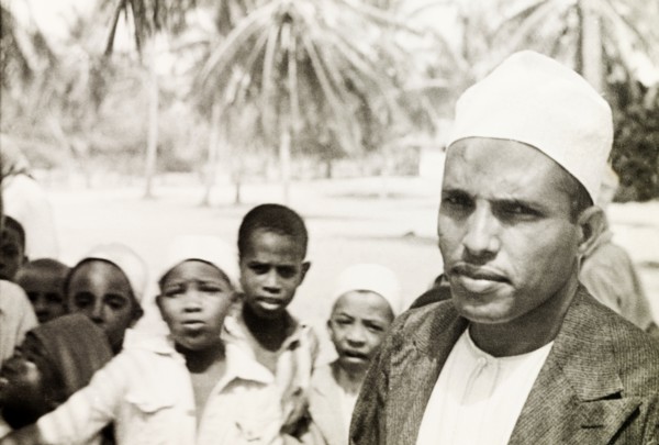 A Surahi type'. A Muslim man (possibly a teacher) stands in front of a group of children, staring