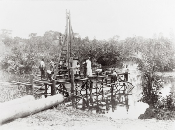 Driving piles into the water. On a wooden scaffolding structure built around a pile driver next to