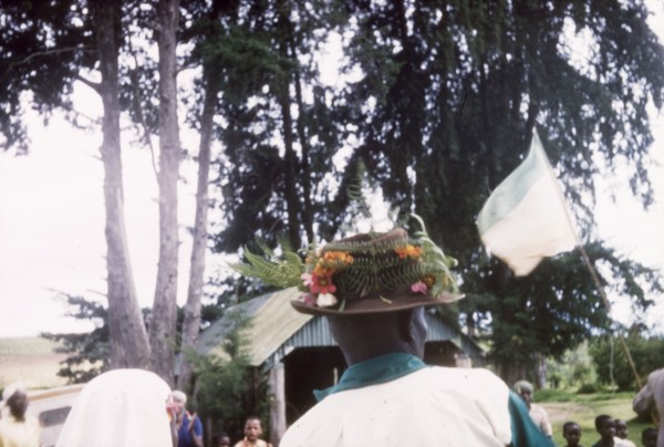 A Christmas hat. Seen from behind, an African man wears a trilby hat decorated with flowers and