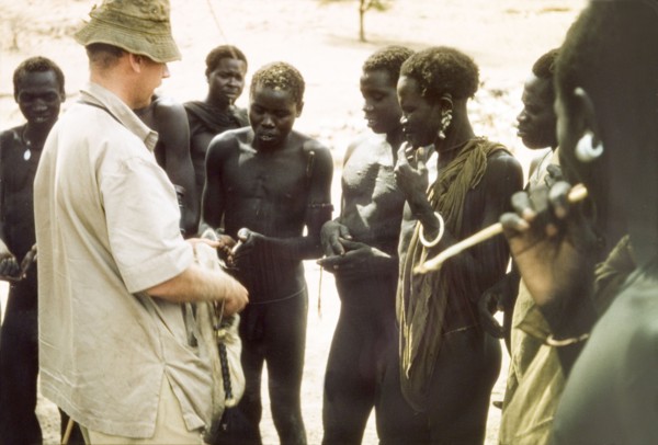Tobacco exchanged for news. British Game Ranger John Blower offers tobacco to a group of Toposa men
