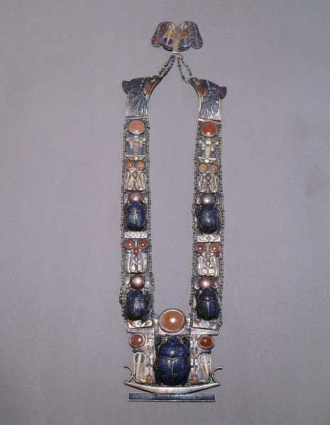 A scarab pectoral from the tomb of Tutankhamun with straps formed from inlaid plaques with uraei (cobras), scarabs & solar discs