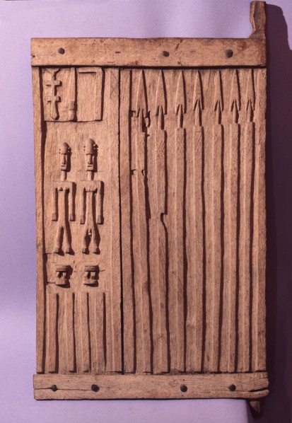A shutter like door from a Dogon granary sculpted with rows of spears, two stools and a couple which may refer to the founding ancestors of the owners family or village