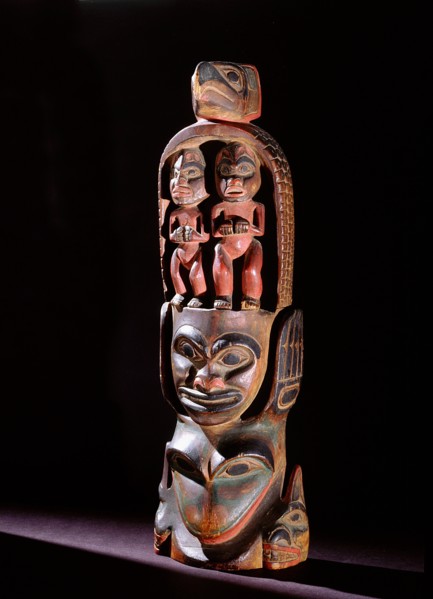 Model totem pole with paired figures below bird crest