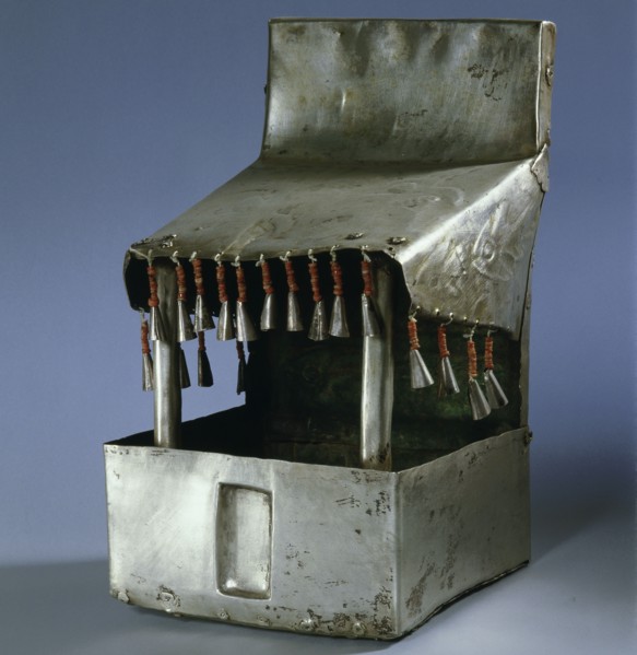 A model temple made of beaten silver, with bell like tassels hanging from the roof
