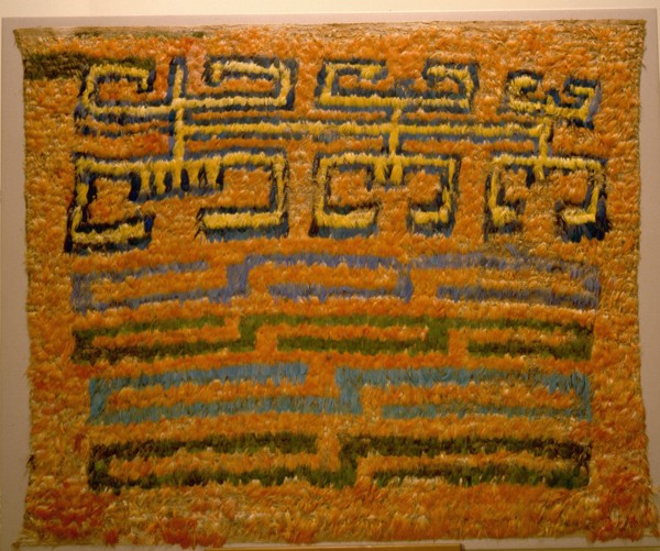 Featherwork tabbard depicting a combination of a tumi knife in the shape of a crescent, two bicephalic dragons and radiant sun faces