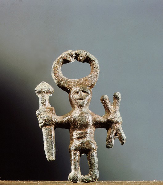 Pendant or amulet of a man holding asword and two spears and wearing ahorned helmet