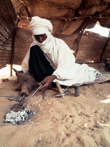 A blacksmith, possibly Tuareg or Songhay, forging iron