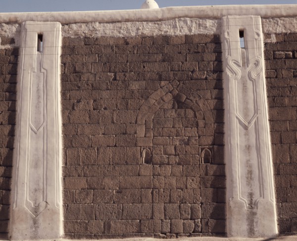 Incised plasterwork pilasters set into an old stone wall