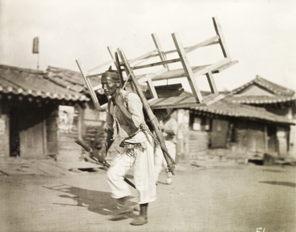 A Korean labourer carries a bench
