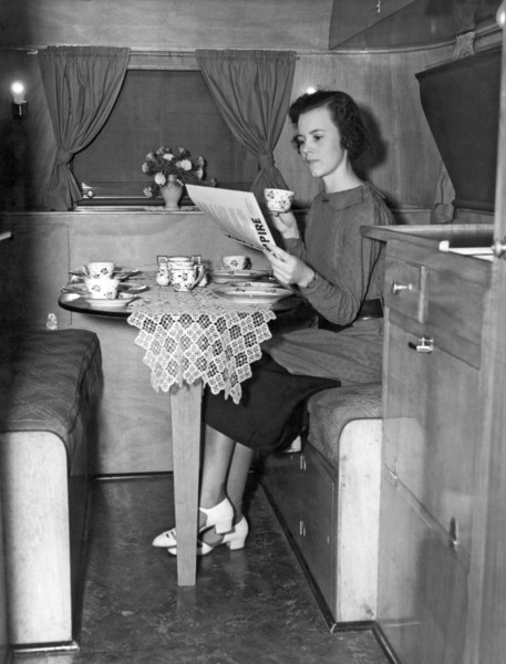 United States:  c. 1936.
A  young woman having breakfast and coffee at a table in a trailer.