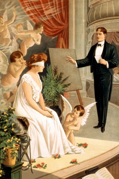 Hypnotist and blindfolded woman with angels on stage 1910